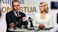 A man, Petteri Orpo, and a woman, Maggie Keskinen, stand at a podium.