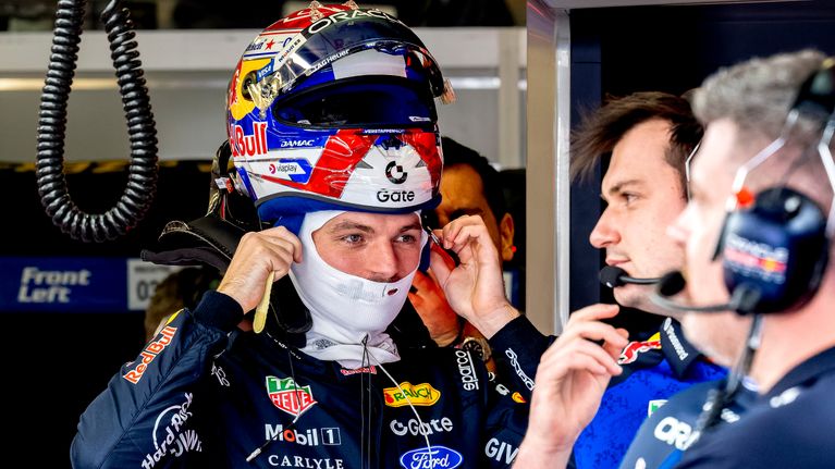 Max Verstappen laittaa kypärää päähänsä.