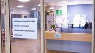 Vastaanottotiski ja lasiseinä, ovessa kyltti jossa lukee kehitysvammapoliklinikka, nuorten kuntoutus, toiminnallinen kuntoutus, neuvonta.
