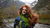 Punahiuksinen drag queen vuoristomaisemassa keväisessä luonnossa joen rannalla.