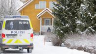 Poliisiauto ja poliisi keltaisen omakotitalon lumisella pihalla.