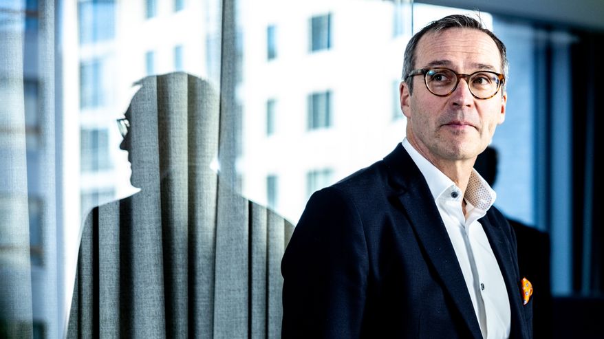 Mikko Kautto seisoo toimistolla lasiseinän edessä johon heijastuu hänen profiilinsa.