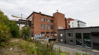 Vanha Näsijärven pahvitehdas Santalahdessa. Rakennus on kärsinyt vaurioita ja sen ikkunat ovat rikki. Vieressä tuore uudisrakennus.