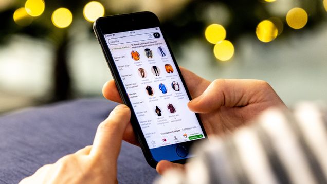 Henkilö selaa puhelimella verkkosivua, jolla myydään erilaisia tuotteita.