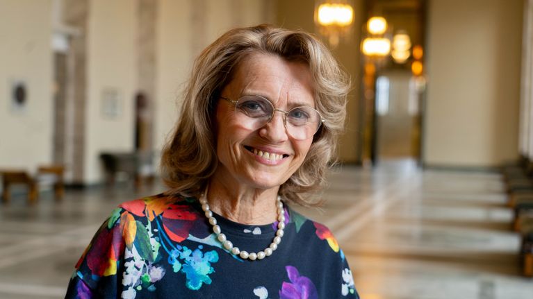 Kvinnlig politiker i riksdagen, som ler brett. 