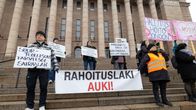 Mielenosoittajia kytteineen eduskuntatalon portailla.