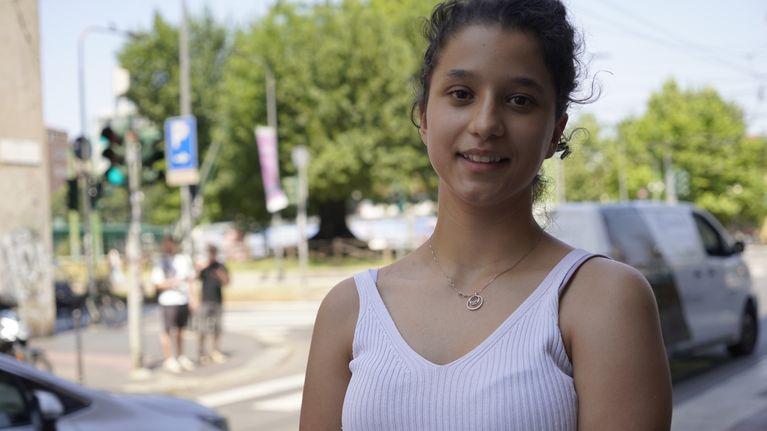 Ung kvinna tittar in i kameran på en gata i Milano.