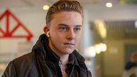 Elis Söderström, tittar förbi kameran. Han har en liten hörlur i ena örat.