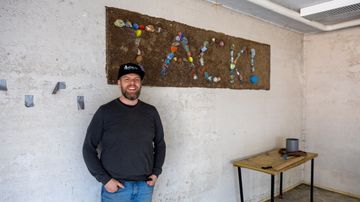 Mathias Blomqvist står framför en vägg med en dekoration där ordet tack är format av olika material.