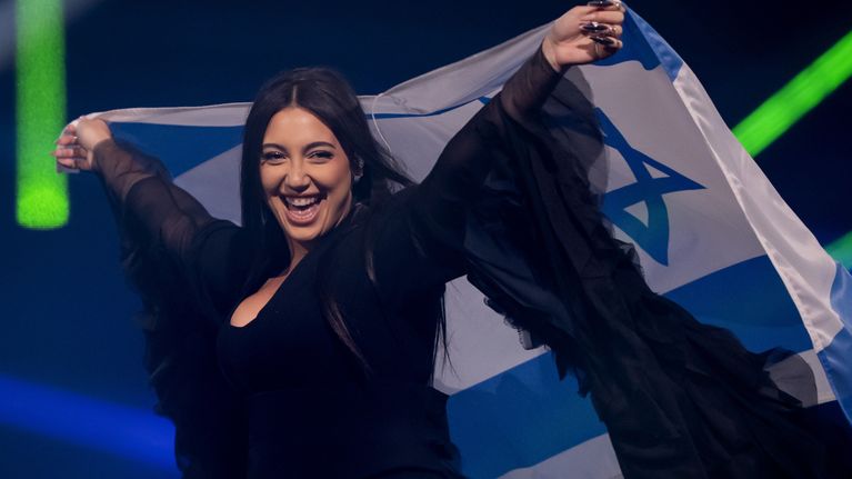 Nainen pitää kädessään Israelin lippua lavalla.