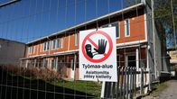 Väliaikainen aita ja varoituskyltti rajaavat työmaa-alueen kerrostalon edustalla.