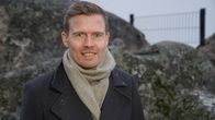 Juho Kostiainen, ekonomisti, Nordea seisoo ulkona kalliopaaden edessä kameraan katsoen.