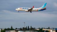 Lentokone, jonka kyljessä lukee "flydubai", lähestyy laskeutumista kaupungin yllä tehdasrakennusten läheisyydessä.