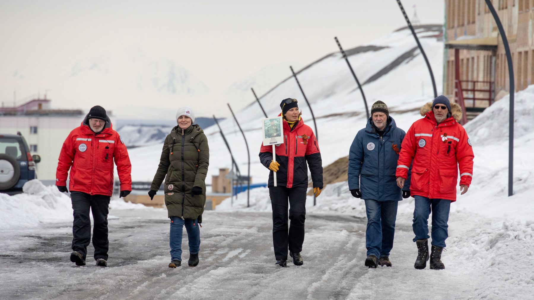Viisi ihmistä kävelemässä katua pitkin Barentsburgissa Venäjän Voitonpäivän aikaan.