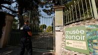 Poliisi seisoo selin suljetun koristeellisen portin edustalla. Portin viereen on kiinnitetty kyltti, jossa opastetaan suuntaa museon parkkipaikalle.