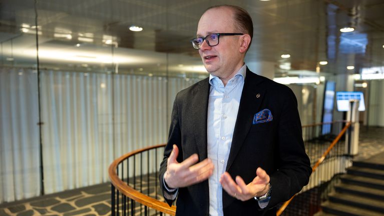 En man viftar med händerna framför en trappa.