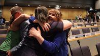 Flera personer kramas i ett auditorium.