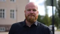 Isak Vilander står framför en stenbyggnad. 