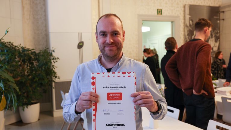 Kuvassa mies hymyilee apuarahapalkinnon kanssa.