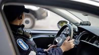 poliisi istuu poliisiauton ratissa.