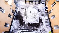 Looking down from an upper floor of an older pale-orange apartment building into a snowy inner courtyard.