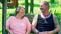 Raija ja Stefan Andersén istuvat vierekkäin pihakeinussa ja nauravat.