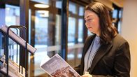 En kvinna, Annika Saarinen i svart kavaj och blå blus läser en turistbroschyr om Borgå. 