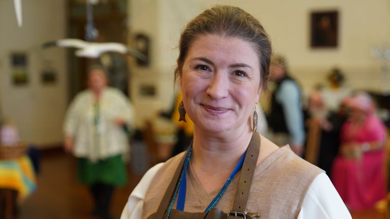 Hoivakoti Helena Helsinki, Anna Tchervinskij, laatu- ja kehitysjohtaja seisoo hoivakodin maalaismarkkina-päivänä hoivakodin salissa kameraan katsoen.