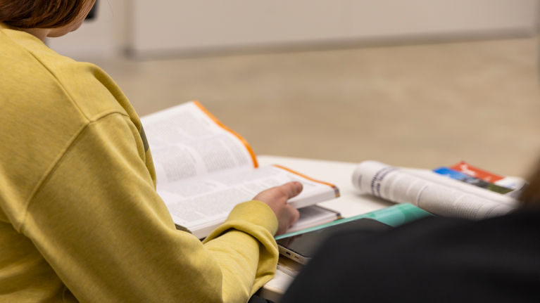 A person sits studying a book.