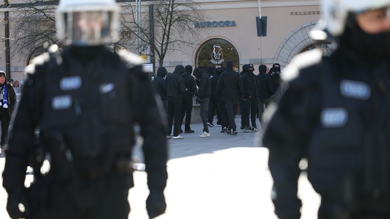 Poliiseja etualalla, mustiin pukeutuneita mielenosoittajia taustalla.