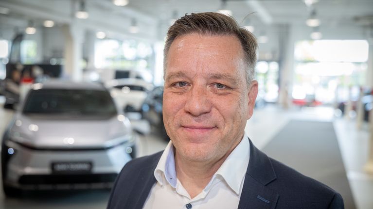 Tero Lausala står i en bilaffär ikädd kostym.