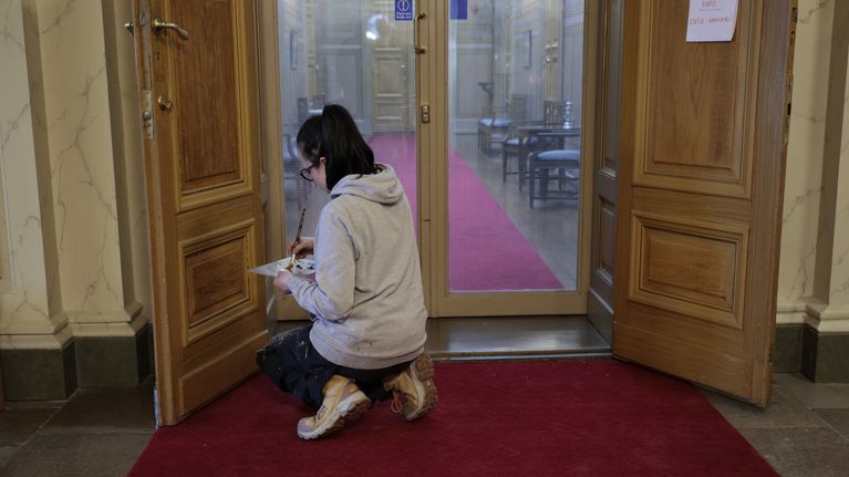 En kvinna restaurerar Vasa hovrätts dörr inomhus.