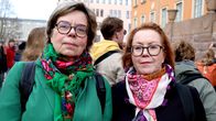 Två personer med färgglada halsdukar står utomhus i en folksamling.