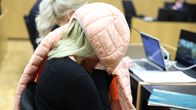 Murhasta epäilty äiti Länsi-Uudenmaan käräjäoikeudessa. Hän on peittänyt kasvonsa vaalenapunaisella takilla.