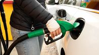 Close up photo of a person at a petrol pump filling up a car with fuel.