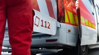 Parkissa oleva ambulanssi ja auton ulkopuoilella oleva ensihoitaja.