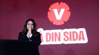 En person står vid ett svart podium framför en röd vägg med Vänsterpartiets logotyp och texten ”DIN SIDA".