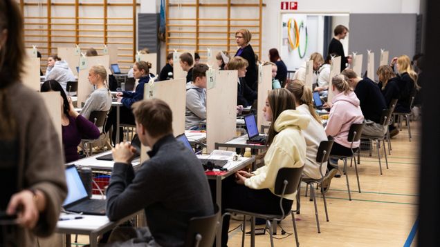 Abiturientit istuvat valmistautumassa ylioppilaskirjoituksiin. 