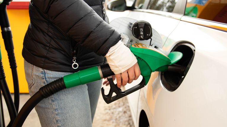 Close up photo of a person at a petrol pump filling up a car with fuel.