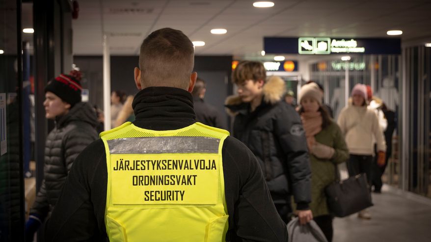 Järjestyksenvalvoja katsoo, kun matkustajat saapuvat lennolta.