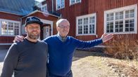 Mathias Blomqvist och Christer Westerholm står utomhus framför en röd träbyggnad med vita fönster.