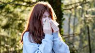 A person blowing their nose outside.