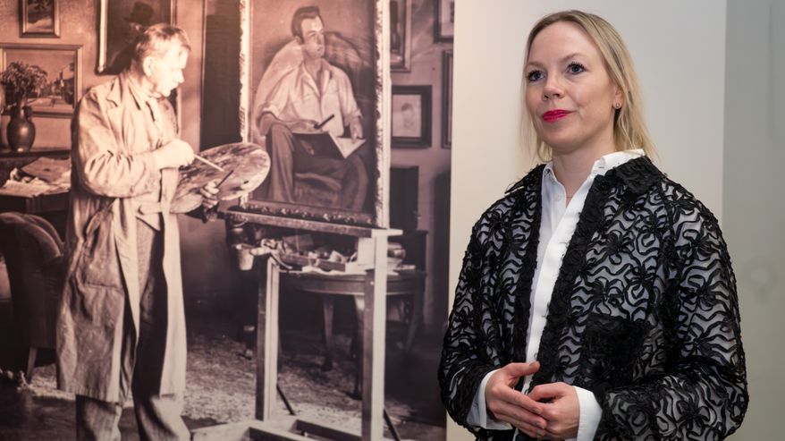 Kuvataiteilija Josefina Nelimarkka. Vieressä suuri mustavalkoinen valokuva, jossa Eero Nelimarkka maalaa ateljeessa.