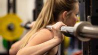 Jenni Virta kuntosalilla tekemässä kyykkyharjoitusta painonnostotangolla.