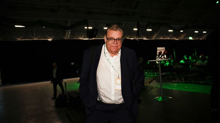 Tmo Soini står i ett funkelt och ganska tomt rum med namnlapp kring halsen.
