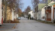 Tre kvinnor går på en tom gata. På vardera sidor syns gamla trähus.