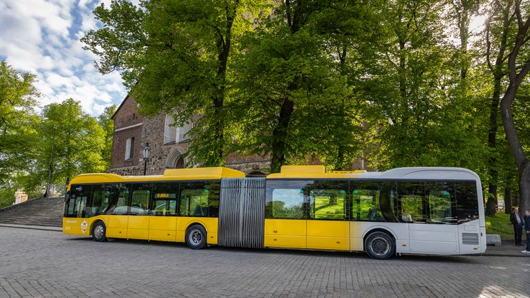 En gulvit buss står parkerad på framför Åbo Domkyrka. 