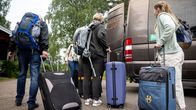 Matkailijat poistumassa majapaikasta linja-autoon mukanaan matkalaukut ja rinkat.