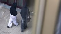 Kaksi muistiin pukeutunutta nuorta ylhäältä päin kuvattuna. Kuvassa ei näy henkilön kasvoja. Vain selät ja reput. 