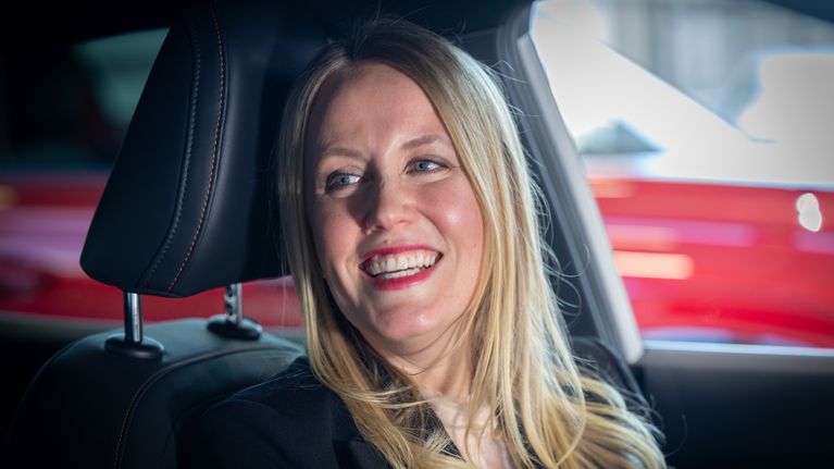Helena Sauramo istuu autossa kuljettajan paikalla.